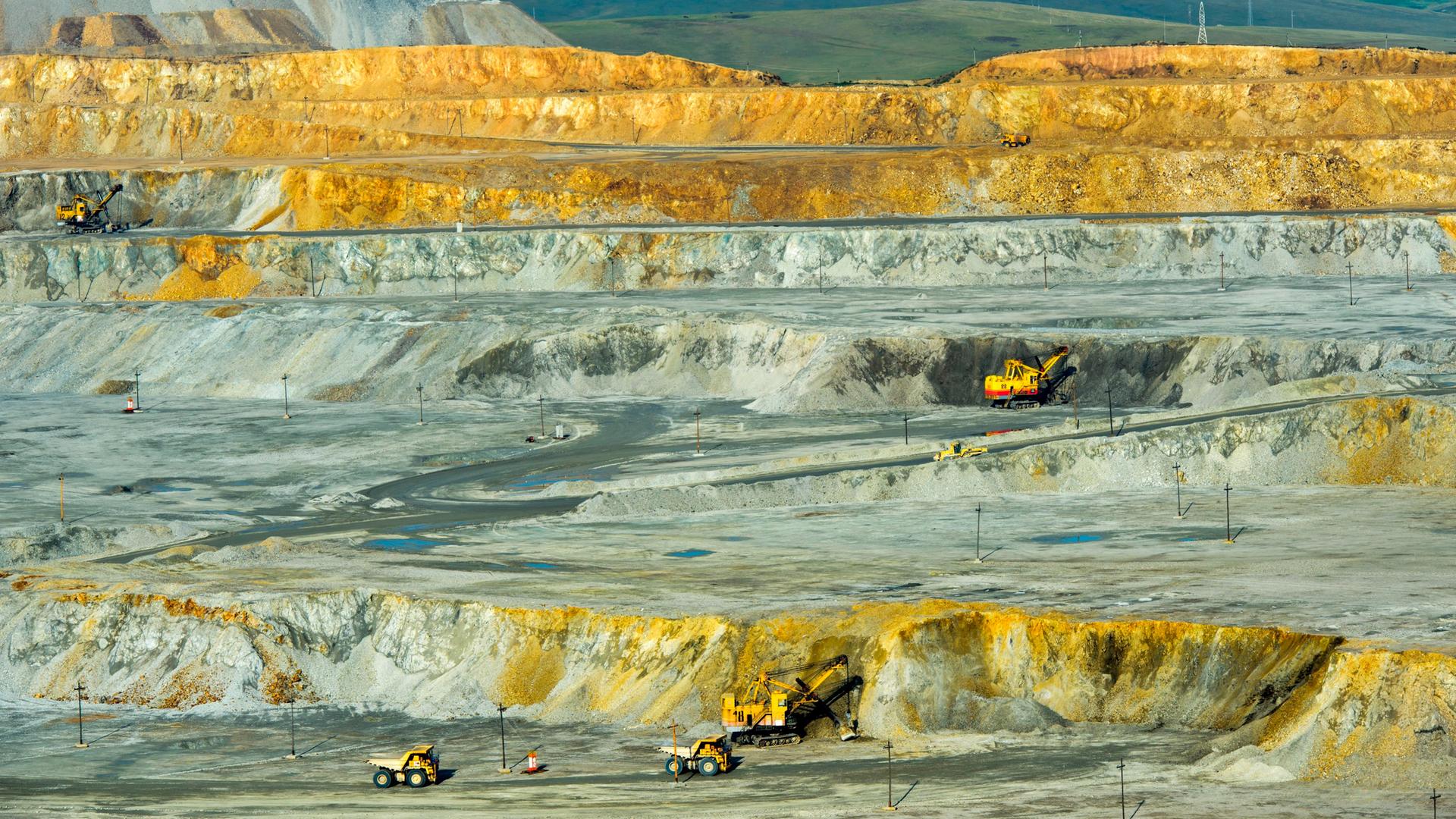 Blick in ein Tagebau-Kupferbergwerk in der Mongolei, mit Baggern und Fahrzeugen