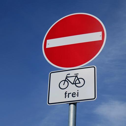 Unter einem Einbahnstraßenschild befindet sich ein Zusatzschild für Fahrräder.