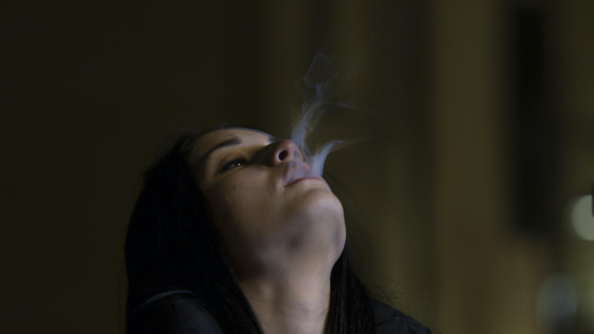Eine Frau lässt Rauch aus ihrem Mund strömen