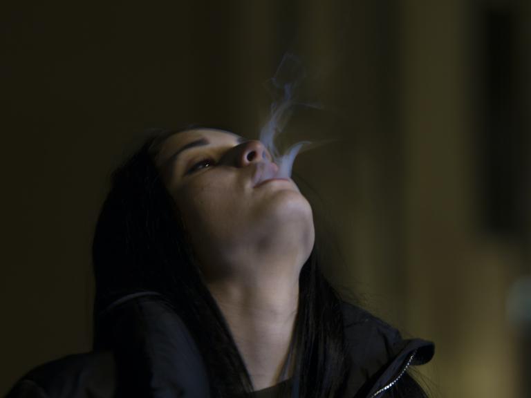 Eine Frau lässt Rauch aus ihrem Mund strömen