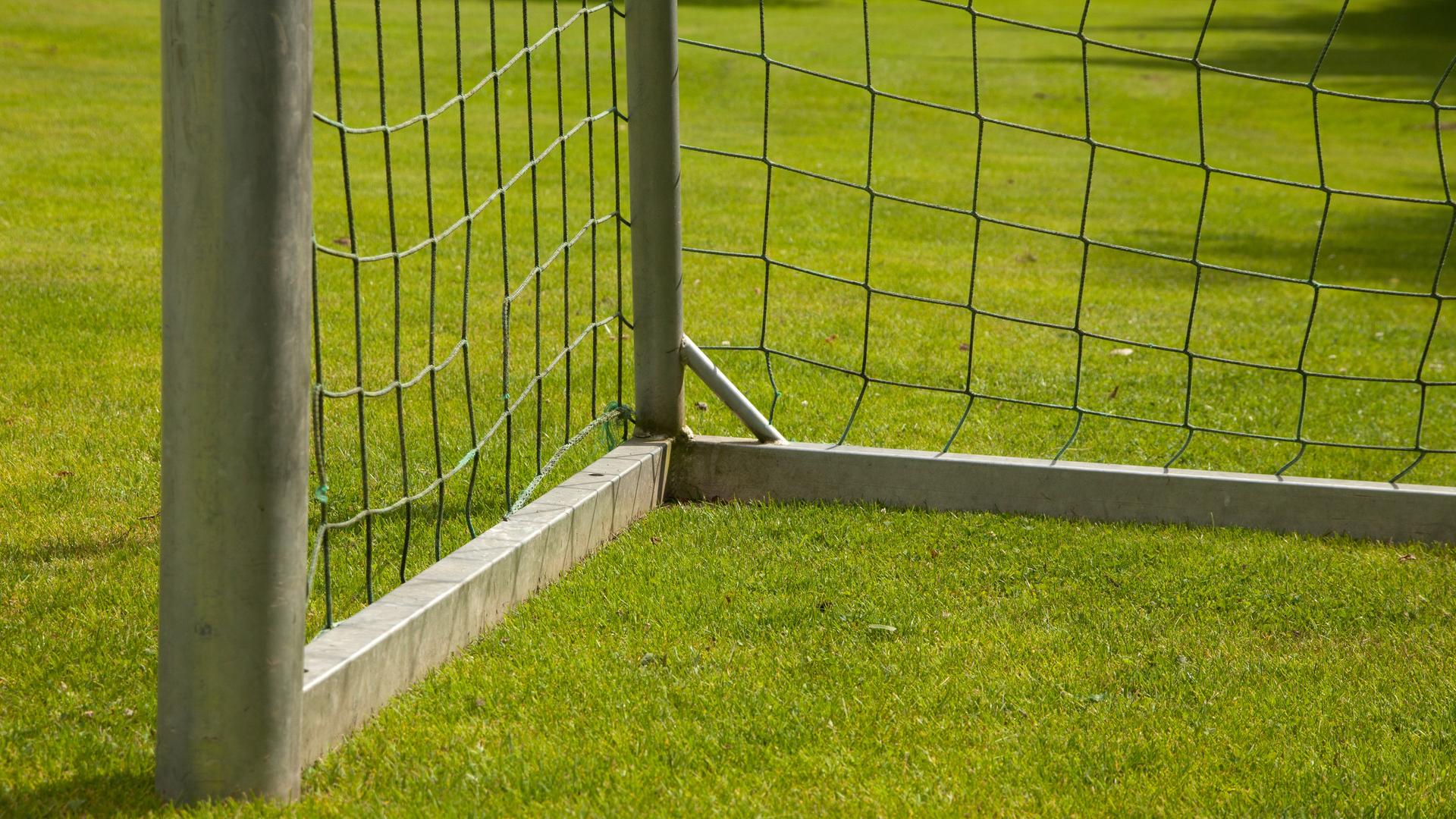 Ein Fußball-Tor steht auf grünem Rasen. Man sieht nur eine Ecke des Tores, nicht das gesamte.