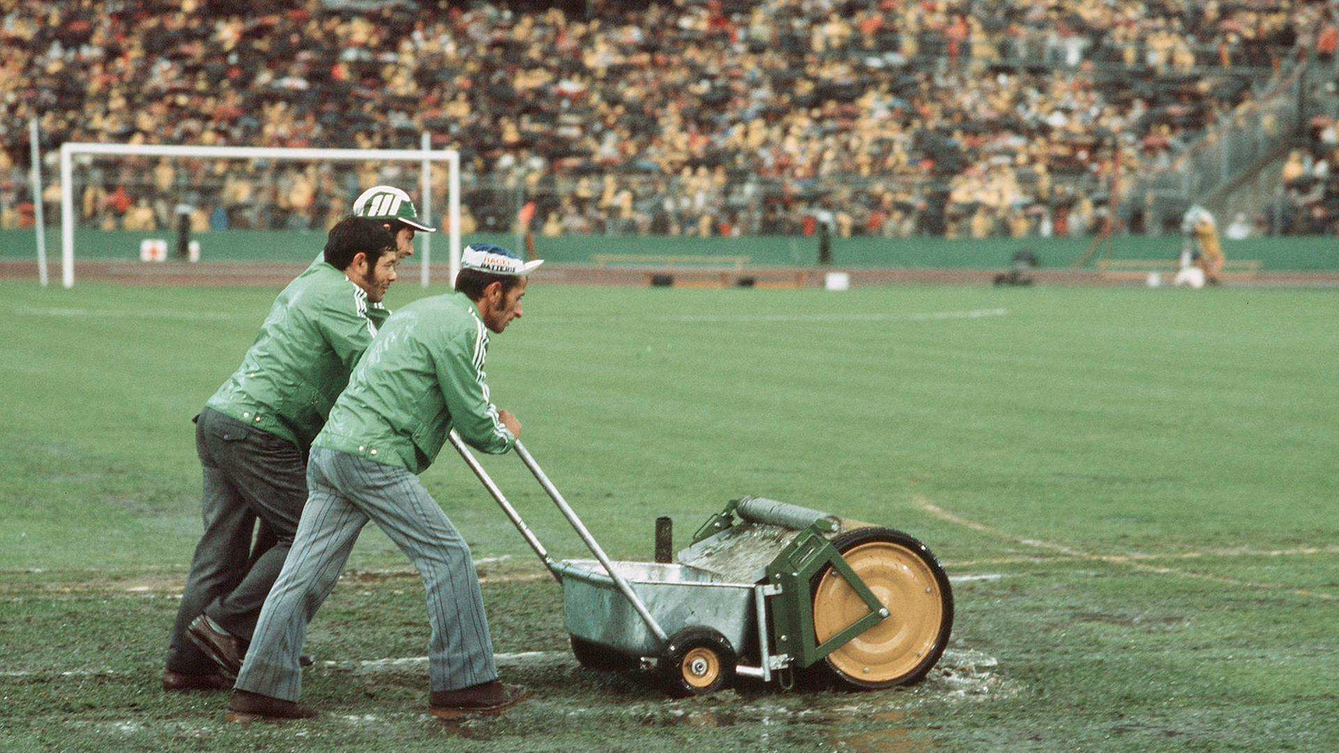 Drei Männer mit einer "Wasserkehrmaschine" beim Spiel Deutschland gegen Polen bei der WM 1974 im Frankfurter Waldstadion