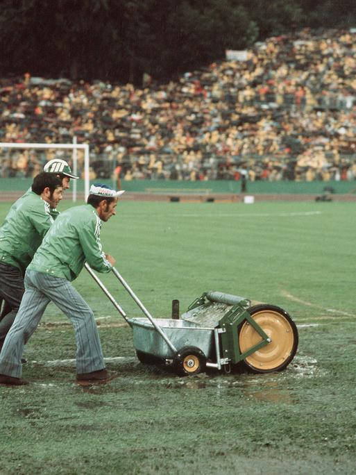 Drei Männer mit einer "Wasserkehrmaschine" beim Spiel Deutschland gegen Polen bei der WM 1974 im Frankfurter Waldstadion