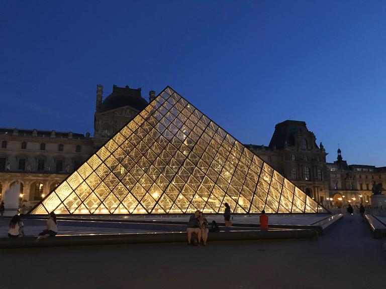 Die Glaspyramide im Innenhof des Louvre beleuchtet bei Nacht.