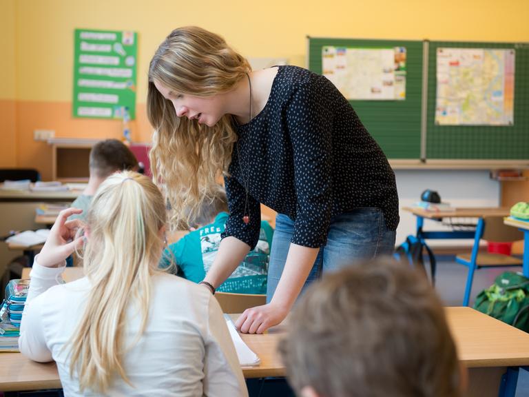 Die Absolventin eines Freiwilligen Sozialen Jahres (FSJ) im Bereich Pädagogik erklärt einer Schülerin in der Grundschule eine Aufgabe.
