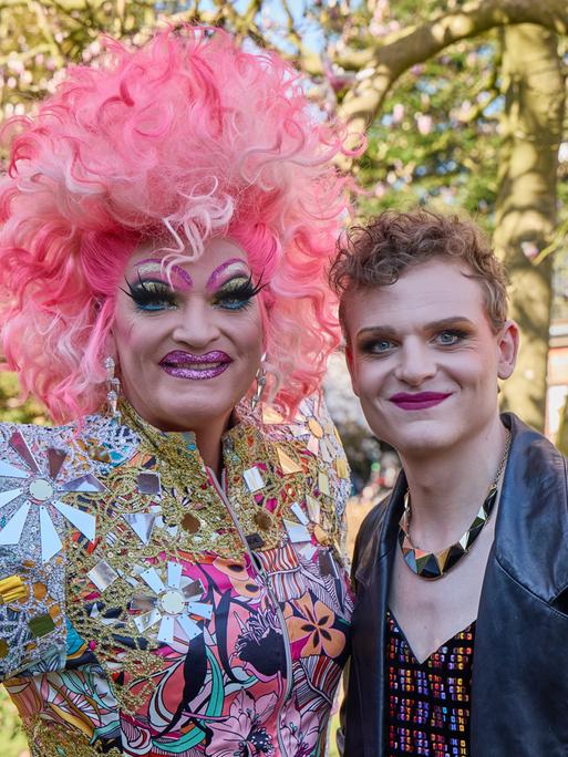 Aufnahme vom Dreh des Films "Olivia". Zwei Menschen stehen dicht beieinander. Es ist die Dragqueen Olivia Jones und der Schauspieler Johannes Hegemann. Beide sind geschminkt und lachen.