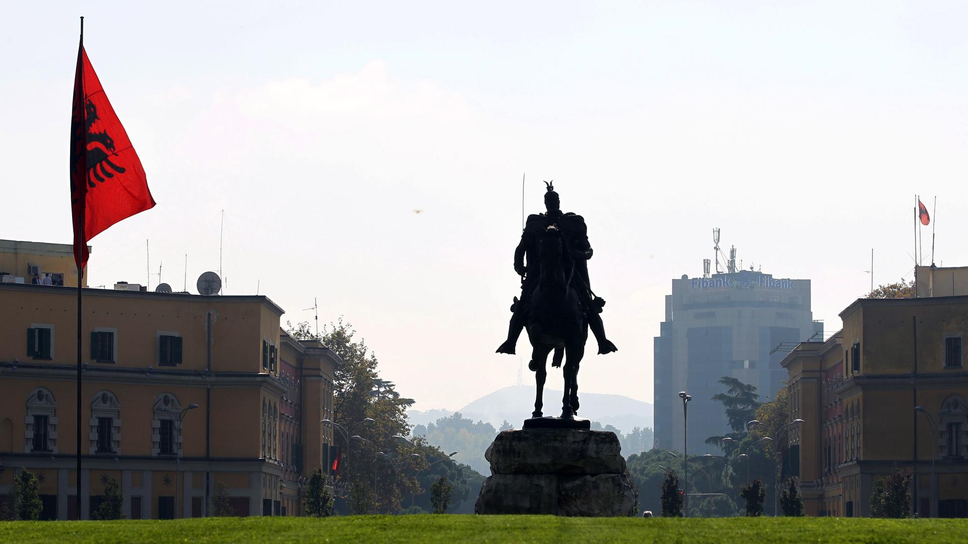 Eine Reiterstatue des albanischen Nationalhelden "Skanderbeg" steht im Stadtzentrum von Tirana neben einer albanischen Flagge.