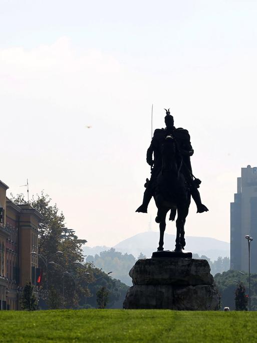 Eine Reiterstatue des albanischen Nationalhelden "Skanderbeg" steht im Stadtzentrum von Tirana neben einer albanischen Flagge.