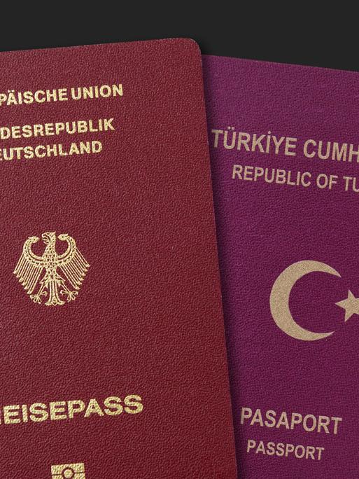 Deutscher und türkischer Pass vor Deutschlandfahne, doppelte Staatsbürgerschaft