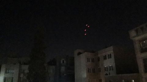 Im dunklen Nachthimmel über einer Stadt sind vier Raketen zu erkennen.