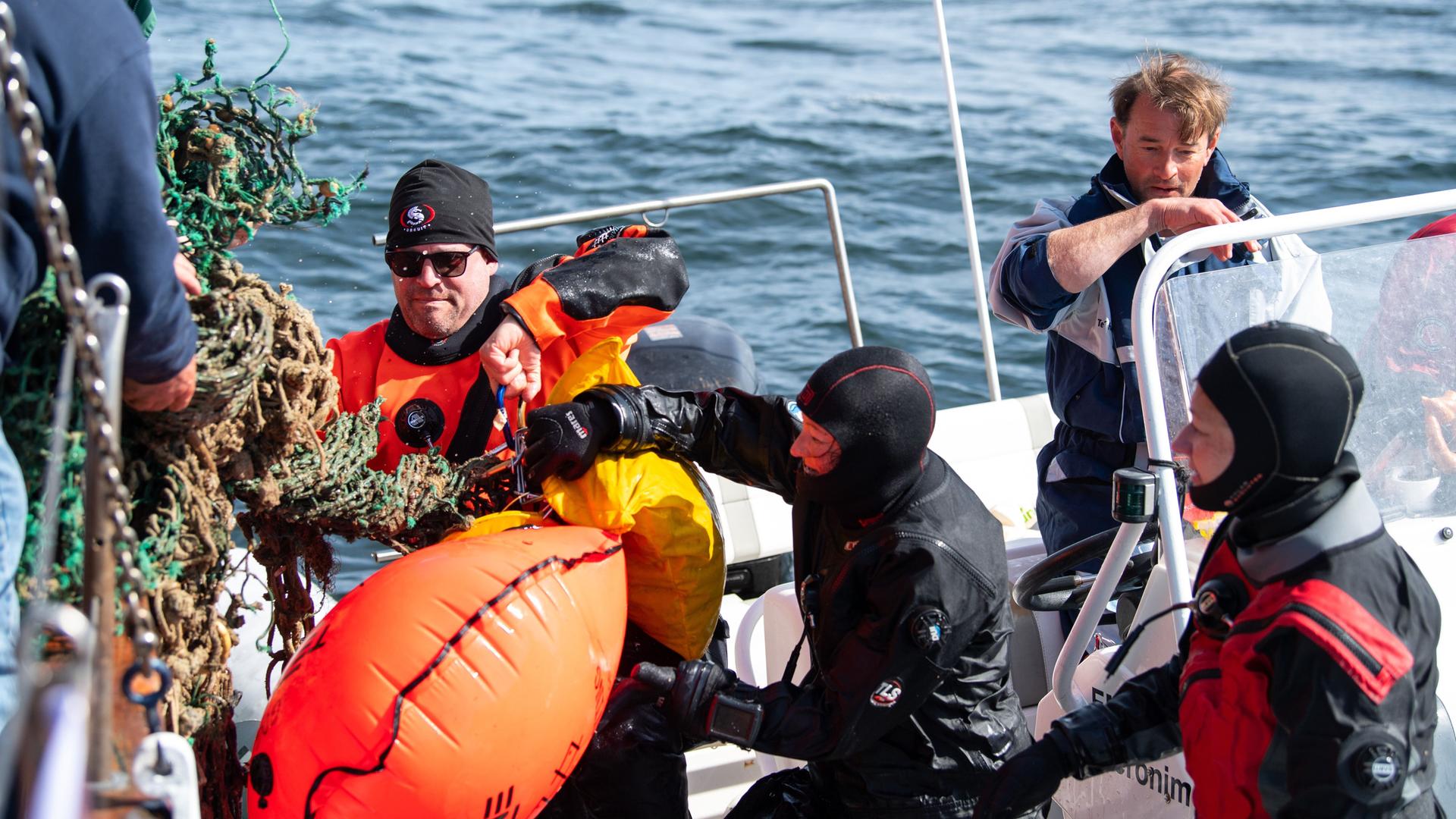 Die Tauchergruppe der Ghost Diving Germany übergibt ein gefundenes Geisternetz an die Besatzung des Kutters. Bei der Aktion "Geisternetze Ostfriesland" suchen Taucher verloren gegangene Geisternetze. Die einwöchige Aktion soll auf die Vermüllung der Meere aufmerksam machen. Vor den ostfriesischen Inseln suchen die professionellen Taucher nach den herrenlosen Netzen.