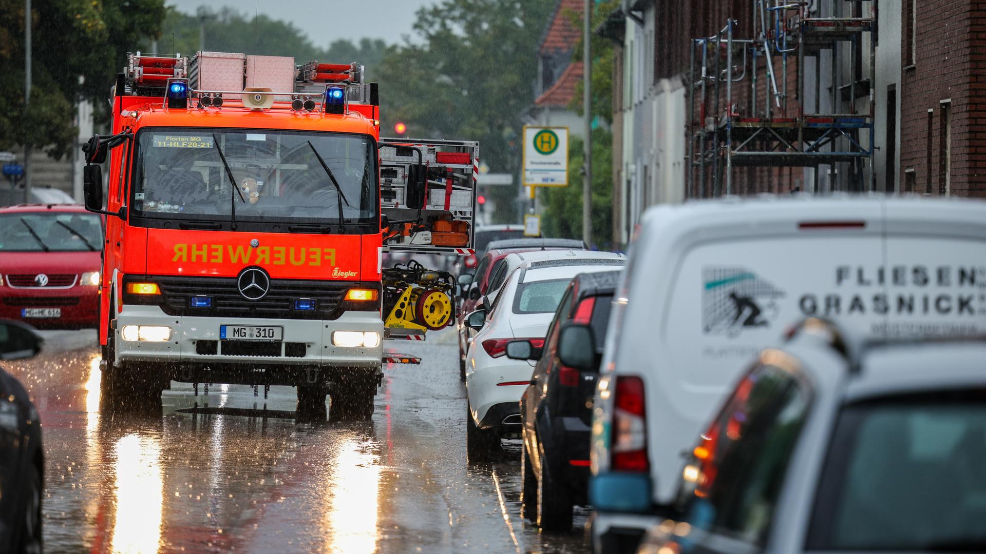 Ein Feuerwehr-Auto steht auf der Straße in der Stadt Mönchengladbach. Die Straße ist nass vom Regen. Ein Feuerwehr-Auto steht auf der Straße in der Stadt Mönchengladbach. Die Straße ist nass vom Regen.