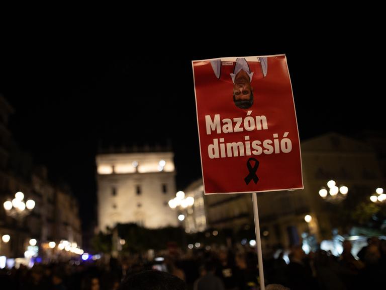 Demonstranten in Valencia halten am 30. November 2024 ein Schild in die Höhe mit der Aufschrift "Mazón dimissió".
