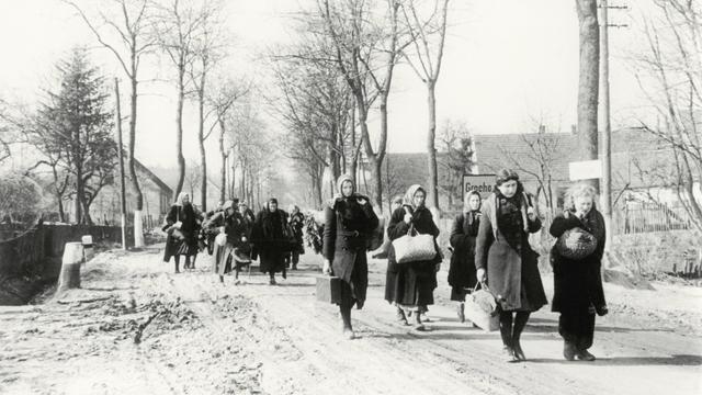 Eine Gruppe Vertriebener zieht 1946 durch das Dorf Grochow.