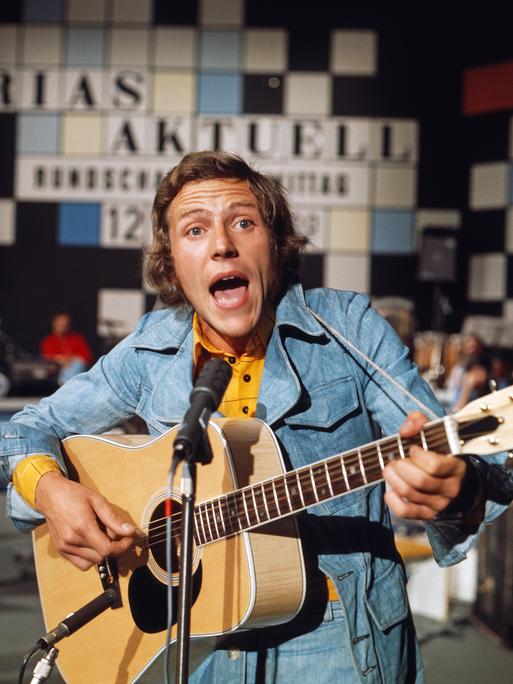Michael Thilo singt in Jeansjacke, Im Hintergrund das Logo der Sendung "Rias aktuell". Michael Thilo singt in Jeansjacke, Im Hintergrund das Logo der Sendung "Rias aktuell".
