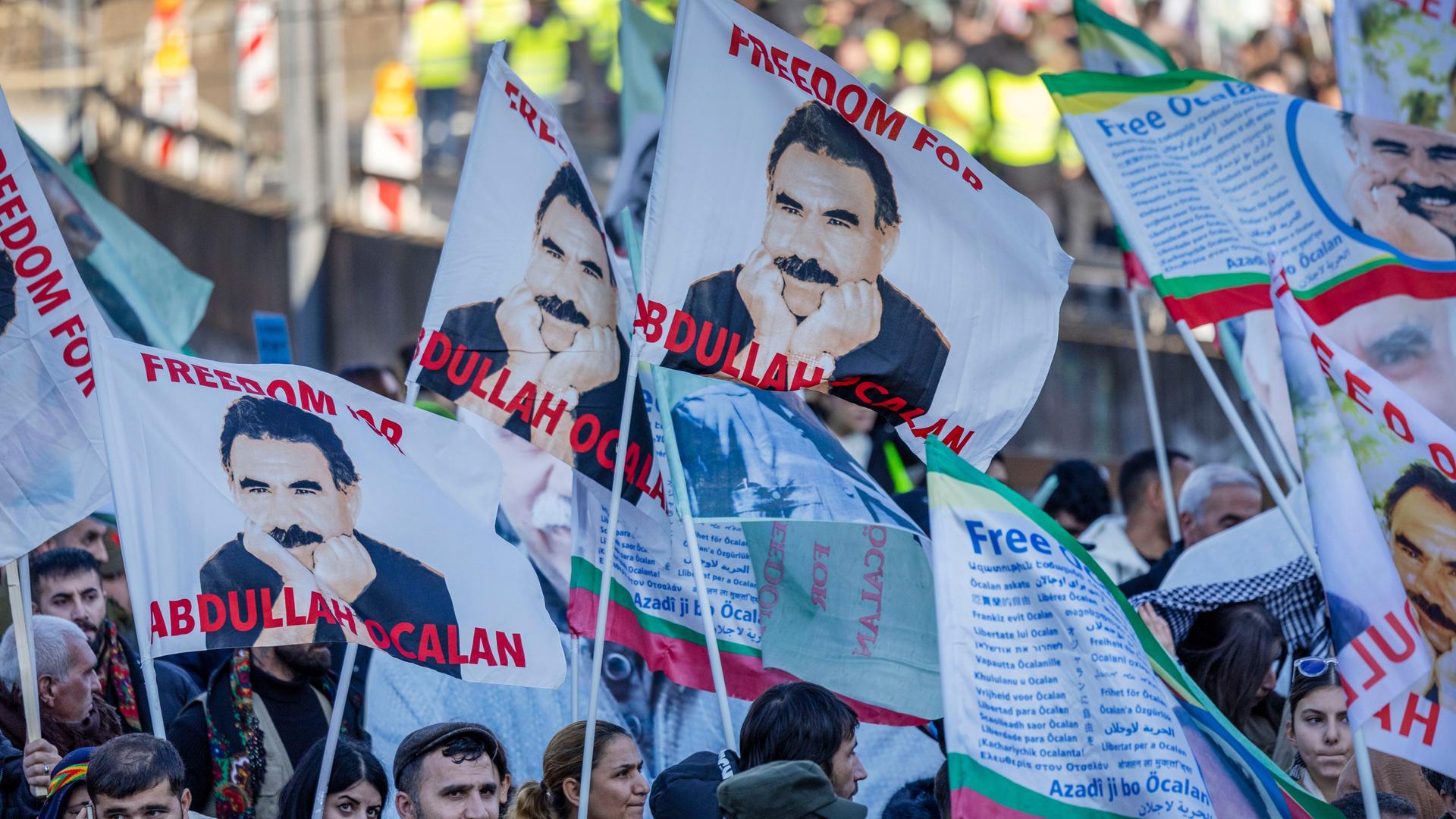 Teilnehmer einer kurdischen Großdemonstration ziehen mit Fahnen durch die Innenstadt. Die Fahnen zeigen den PKK-Führer Öcalan.