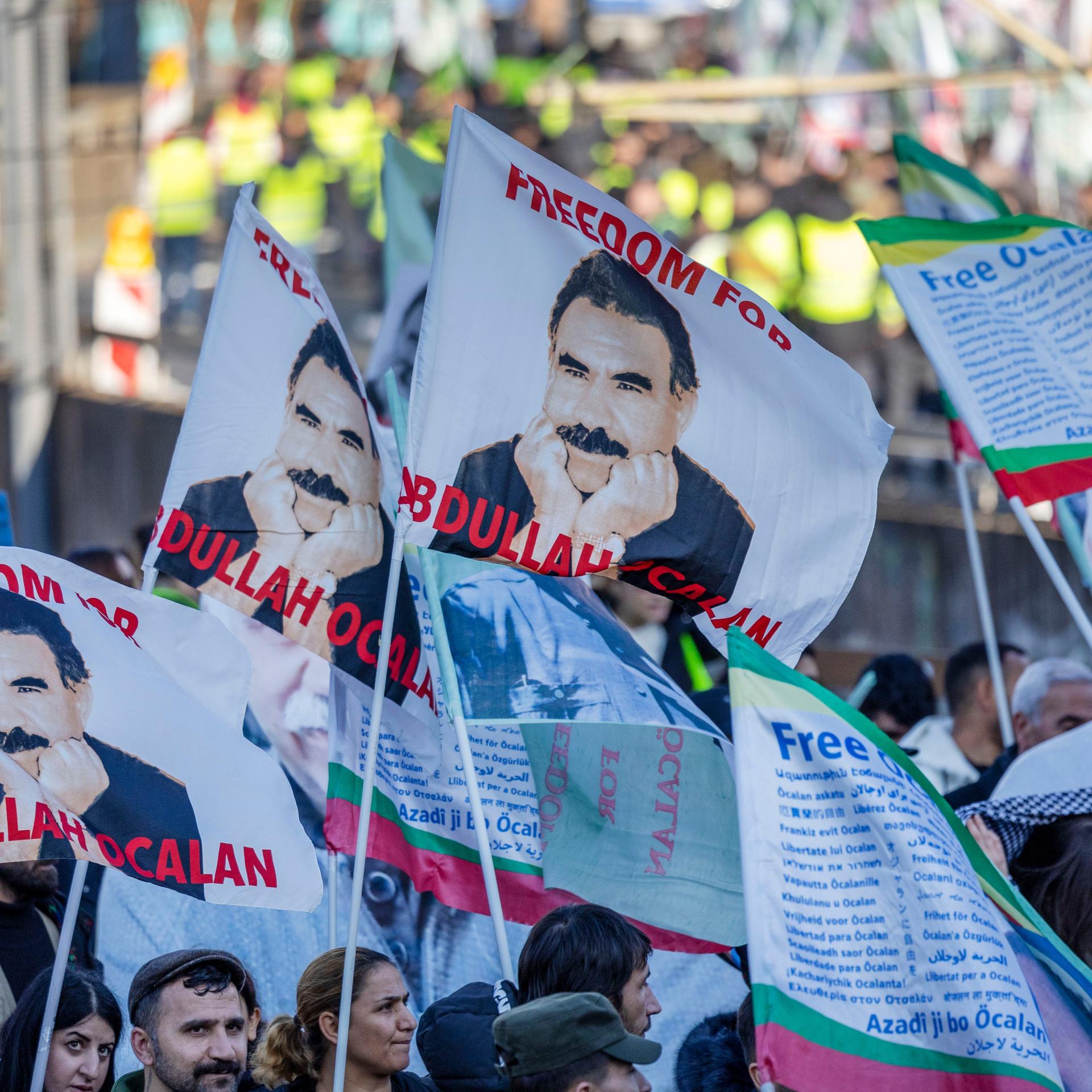 Teilnehmer einer kurdischen Großdemonstration ziehen mit Fahnen durch die Innenstadt. Die Fahnen zeigen den PKK-Führer Öcalan.