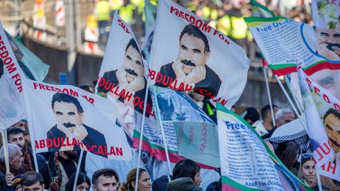 Teilnehmer einer kurdischen Großdemonstration ziehen mit Fahnen durch die Innenstadt. Die Fahnen zeigen den PKK-Führer Öcalan.