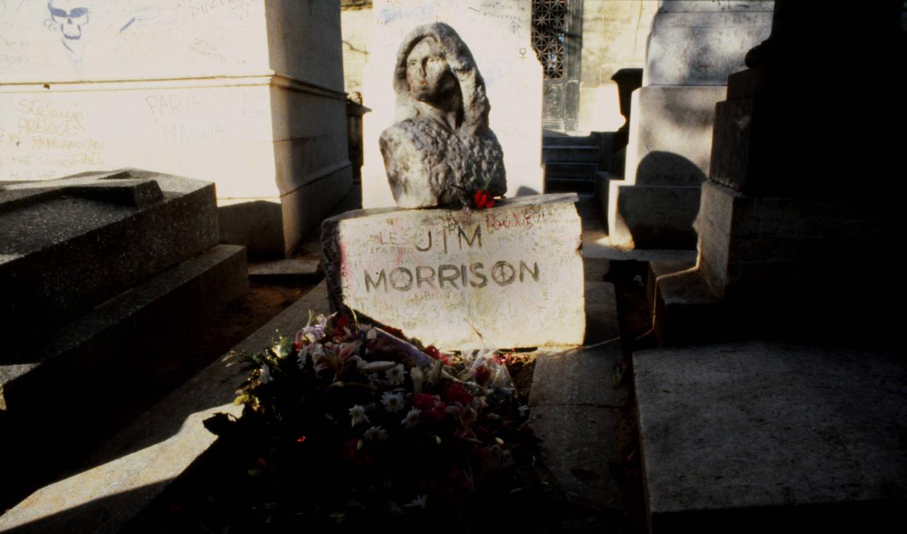 Blick auf das Grab des US-amerikanischen Musikers Jim Morrison, aufgenommen im Jahr 1987. Auf dem Grabstein ist eine steinerne Büste des Oberkörpers des Sängers montiert.