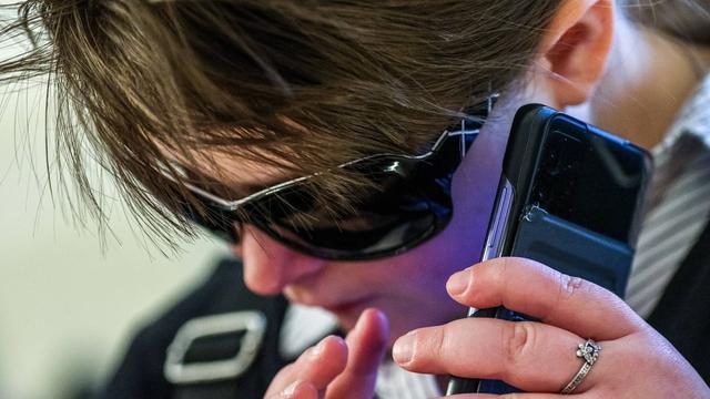 Eine Frau mit dunkler Brille benutzt ein Handy.