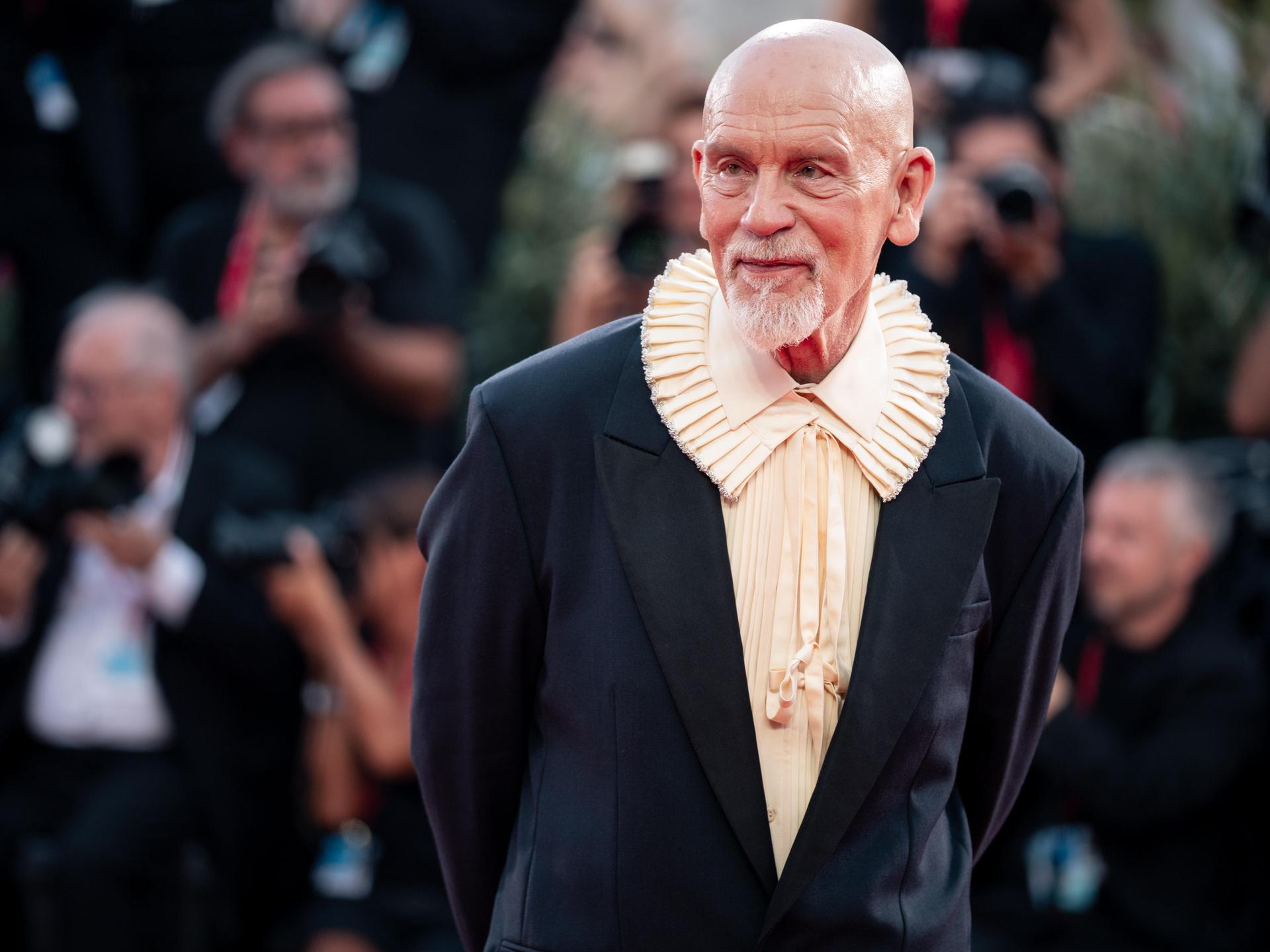 John Malkovich steht auf dem Roten Teppich und lässt sich fotografieren. Er trägt ein Hemd mit extravagantem Kragen. John Malkovich steht auf dem Roten Teppich und lässt sich fotografieren. Er trägt ein Hemd mit extravagantem Kragen.
