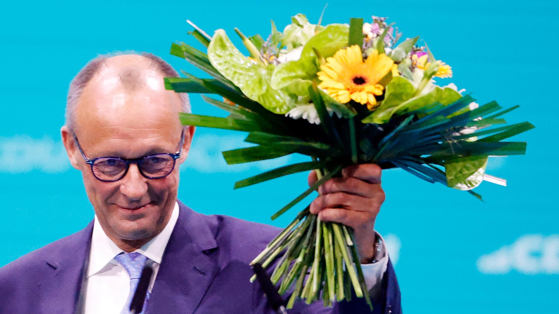 Friedrich Merz, CDU-Bundesvorsitzender, hält seinen Blumenstrauß nach der Wahl zum Bundesvorsitzenden beim CDU-Bundesparteitag hoch. 