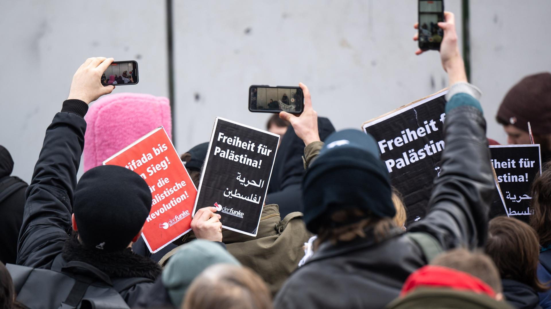 Teilnehmer der propalästinensischen Kundgebung unter dem Motto "Solidarität mit Palästina" stehen vor der Mensa II an der Freien Universität (FU) und halten Schilder mit der Aufschrift "Freiheit für Palästina" hoch. 