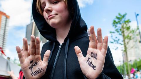 Ein junger Demonstrant zeigt seine Hände, auf denen geschrieben steht: "In your Hands - Our Future", zu Deutsch: "In deinen Händen - unsere Zukunft"