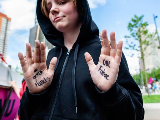 Ein junger Demonstrant zeigt seine Hände, auf denen geschrieben steht: "In your Hands - Our Future", zu Deutsch: "In deinen Händen - unsere Zukunft"