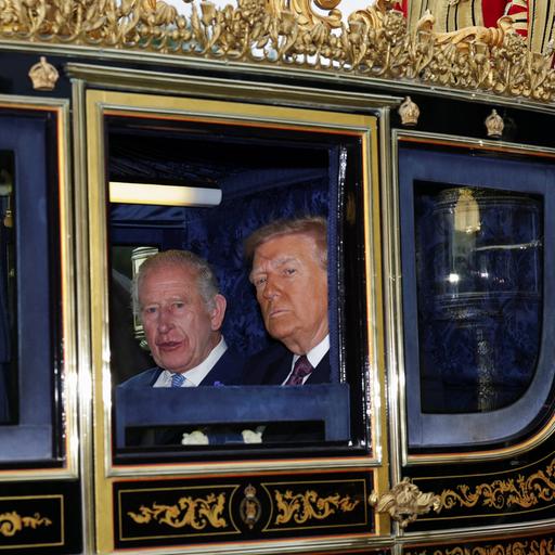US-Präsident Donald Trump und der britische König Charles schauen aus einer goldenen Kutsche heraus in die Kamera.