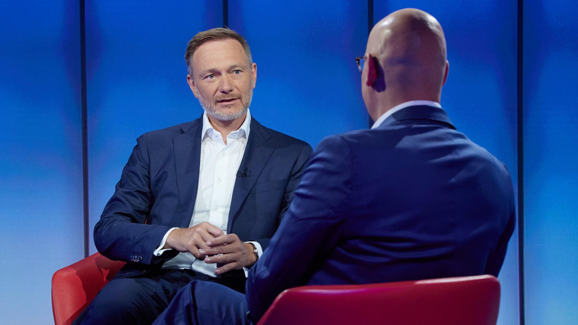 Christian Lindner (FDP, l), Bundesminister der Finanzen, 
sitzt im ARD-Sommerinterview am 28. Juli 2024 in einem TV-Studio, im Vordergrund Moderator Matthias Deiß von hinten.