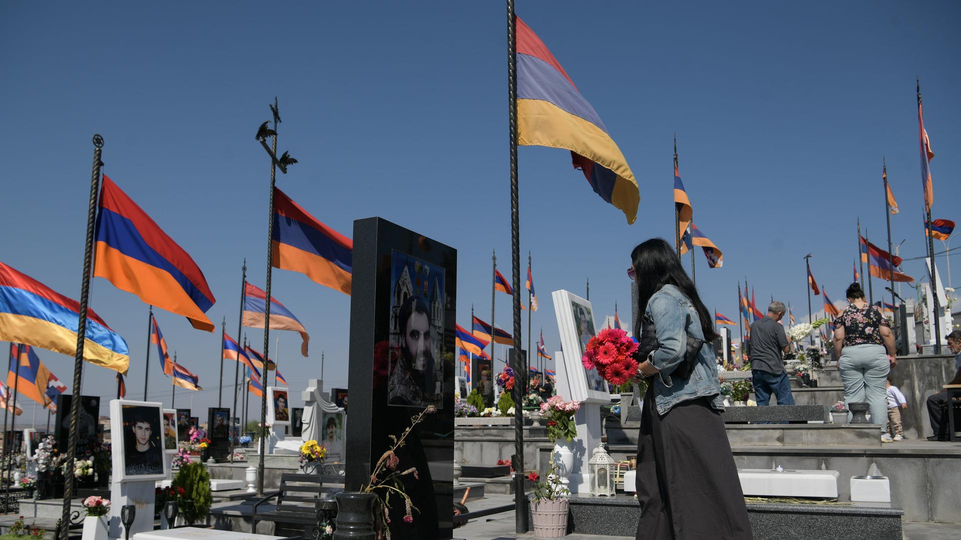 Eine Frau in Armenien besucht einen Friedhof, auf dem Soldaten begraben lieben, die im Konflikt um die armenische Enklave Berg-Karabach in Aserbaidschan gefallen sind. Auf dem Friedhof wehen zahlreiche armenische Flaggen. 