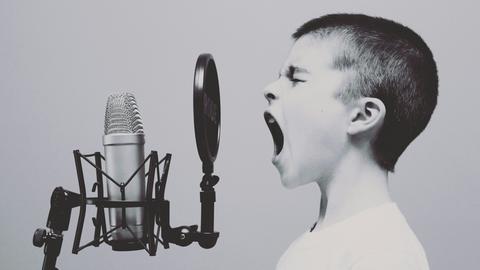 Ein Junge schreit in ein Mikrophon