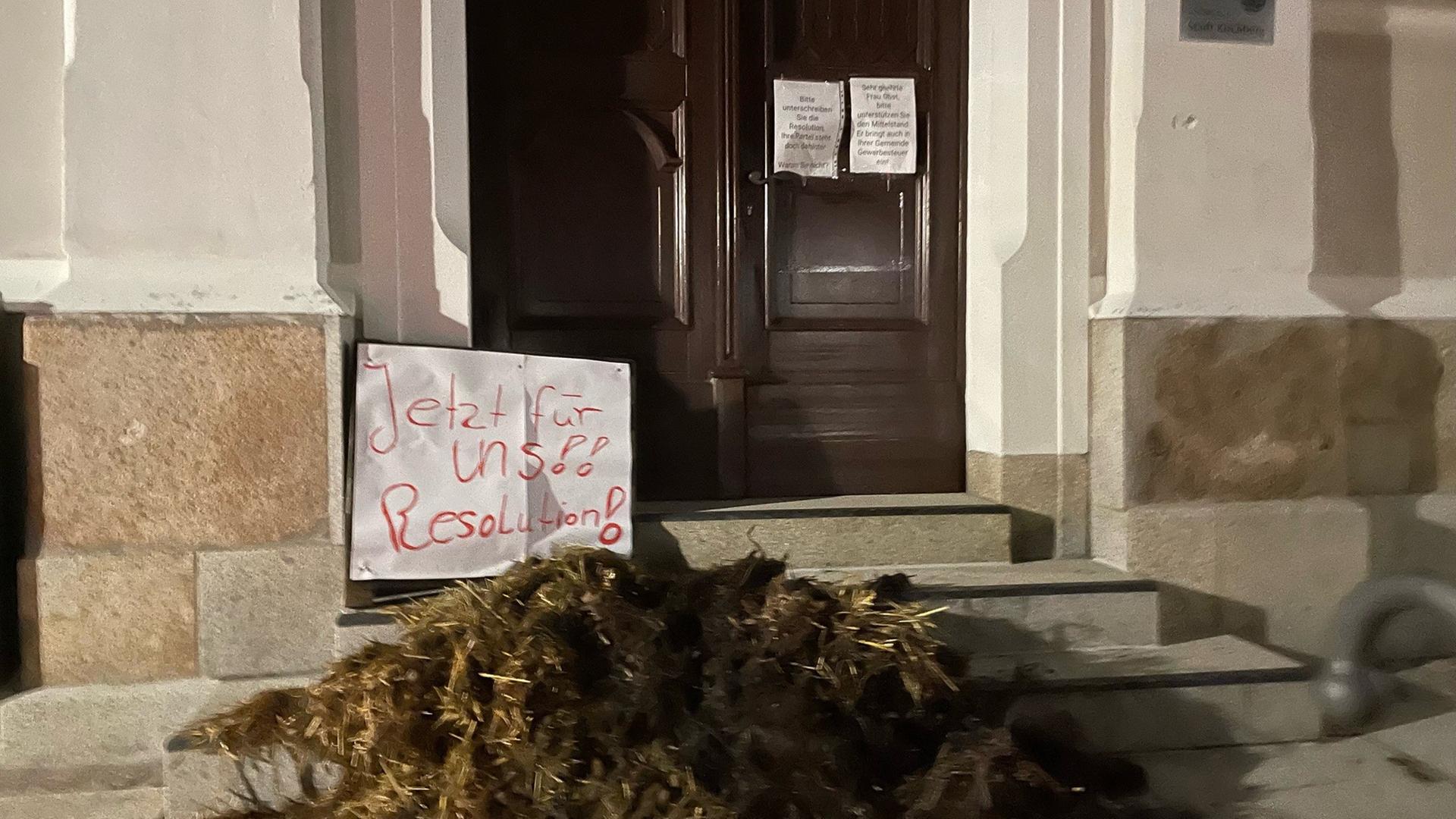 Ein Misthaufen liegt vor dem Rathaus der Stadt. Auf einem Zettel steht "Jetzt für uns! Resolution".