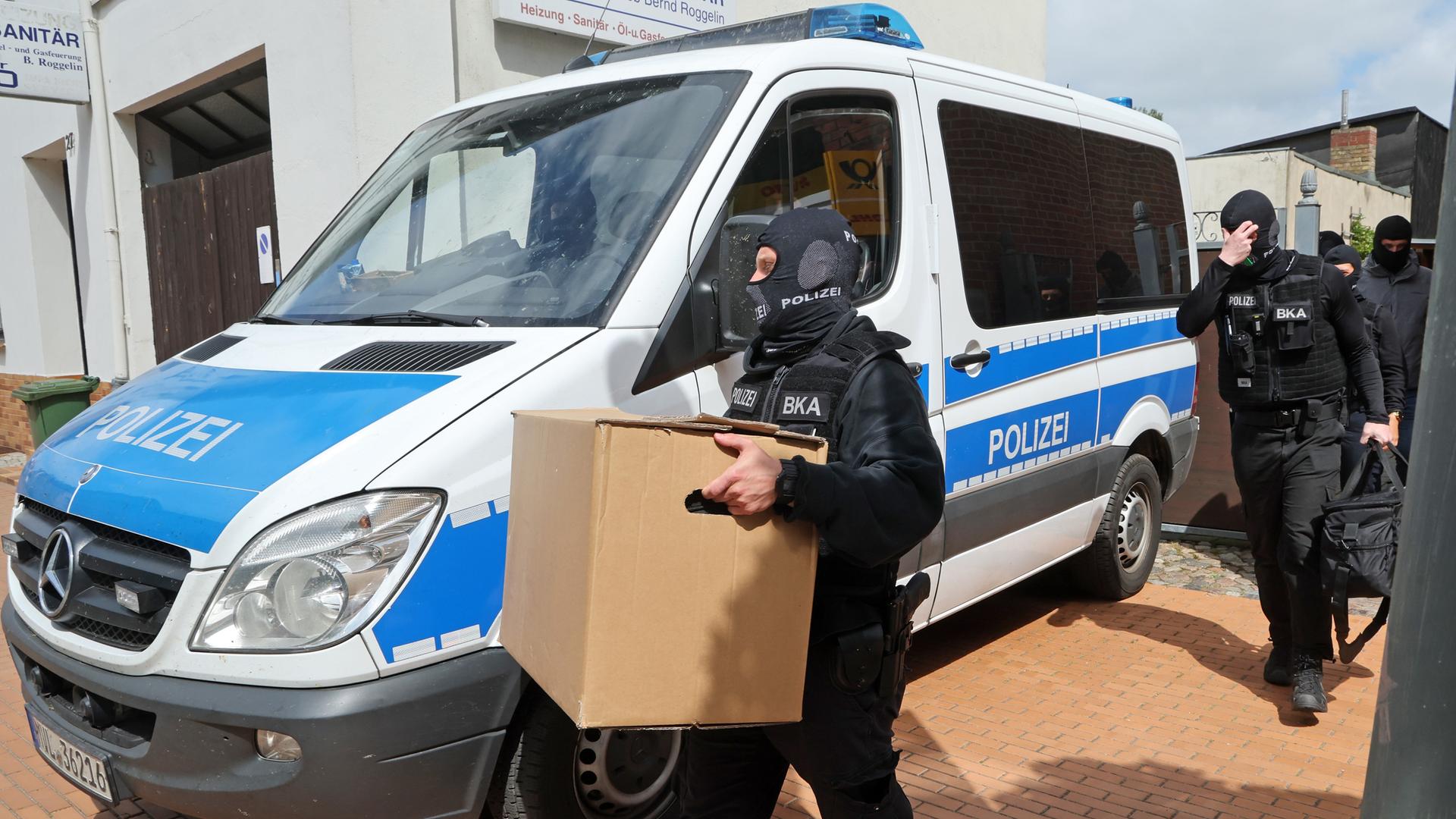 Nach den Durchsuchungen von Räumen im Gebäude "Altes Postamt" kommen die Ermittler mit beschlagnahmtem Material aus dem Haus. 