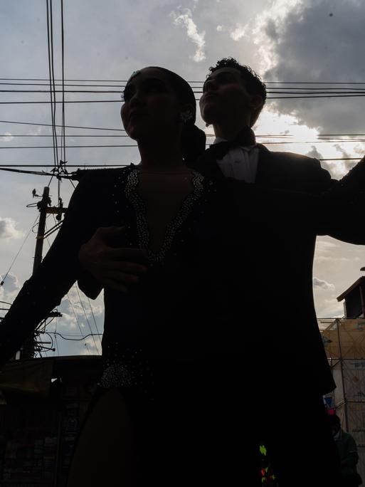 Die Silhouetten von zwei Tango Tanzenden sind unter freiem Himmel zu sehen.