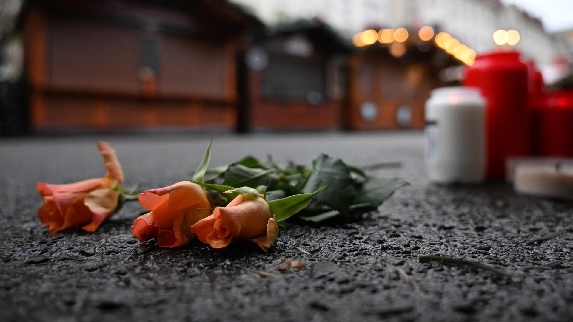 Drei Rosen liegen auf dem Asphalt am Rande des Weihnachtsmarkts in Magdeburg. Aufnahme vom 23.12.2024. 