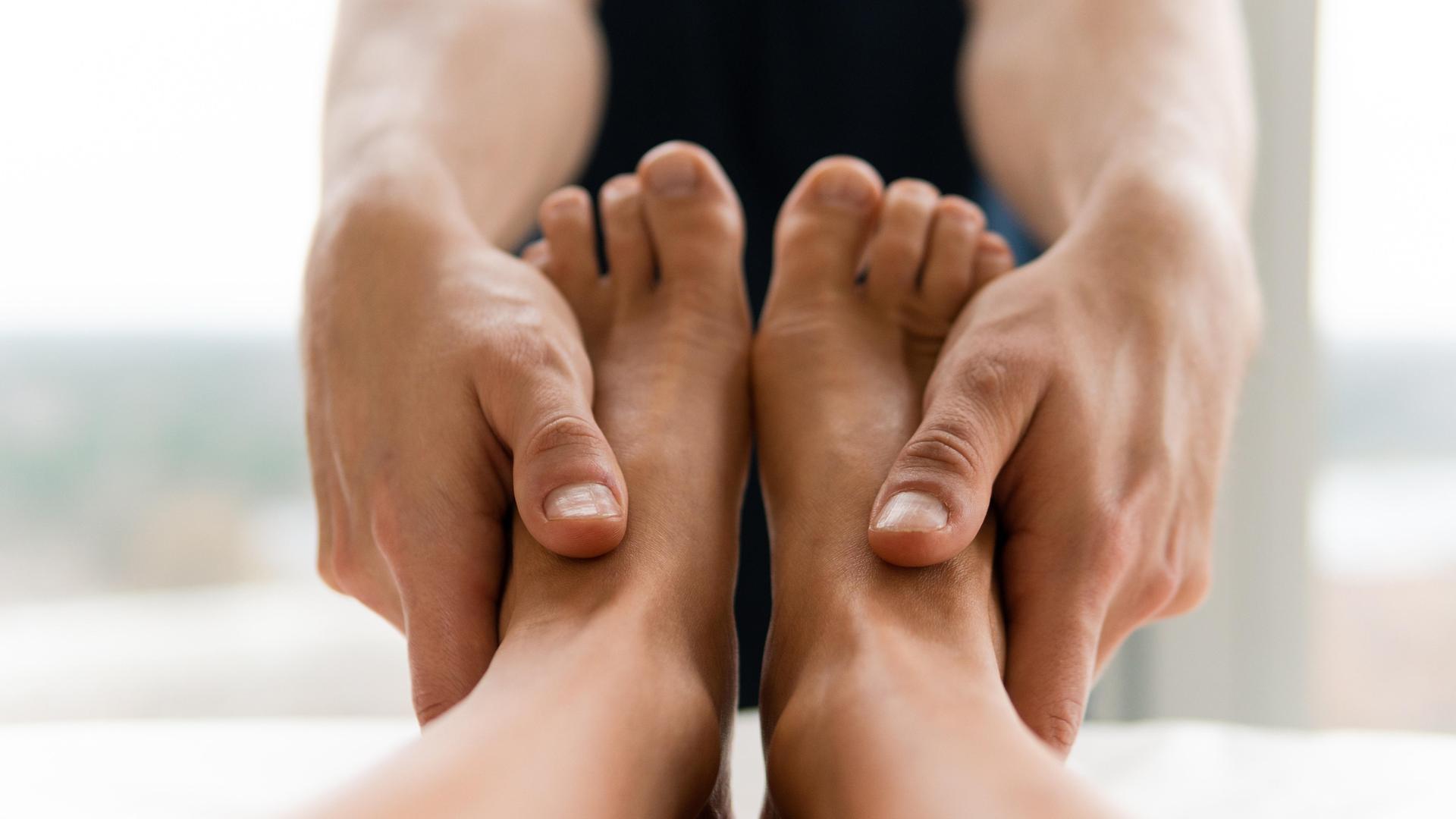 Ein Masseur hat die Hände an ein Paar Füße gelegt. Ein Masseur hat die Hände an ein Paar Füße gelegt.