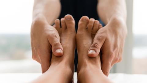 Ein Masseur hat die Hände an ein Paar Füße gelegt. 