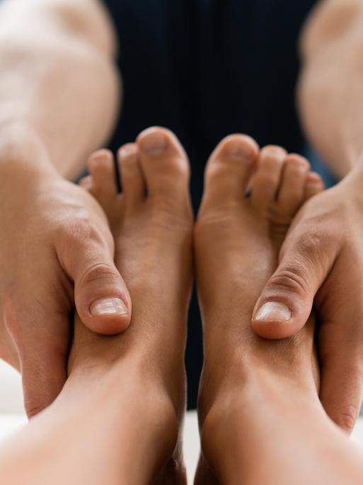 Ein Masseur hat die Hände an ein Paar Füße gelegt. 