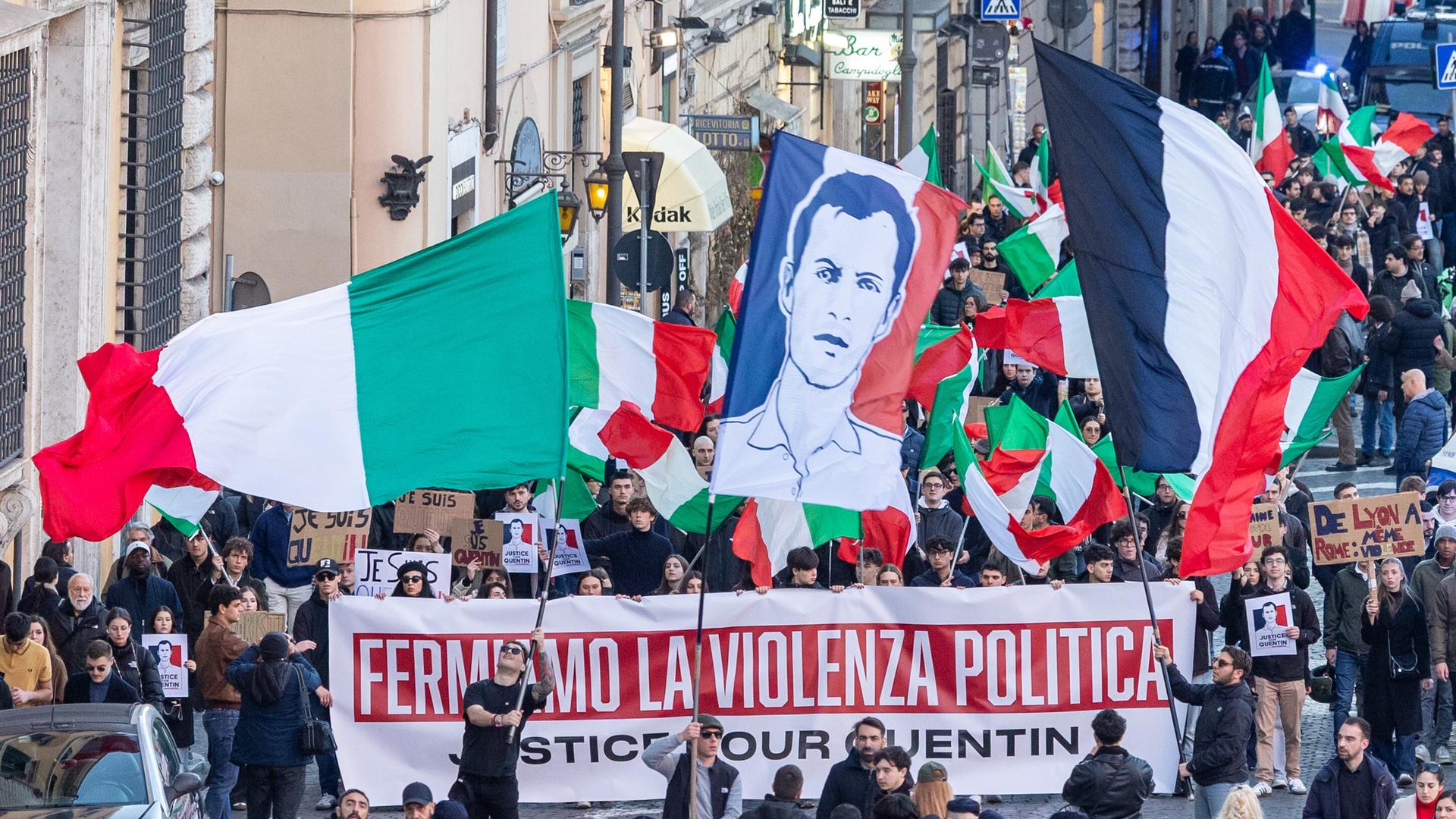 Das Bild zeigt einen Protestzug vieler Menschen in Lyon. Sie tragen Plakate und Banner. Im Vordergrund sind Polizisten zu sehen.