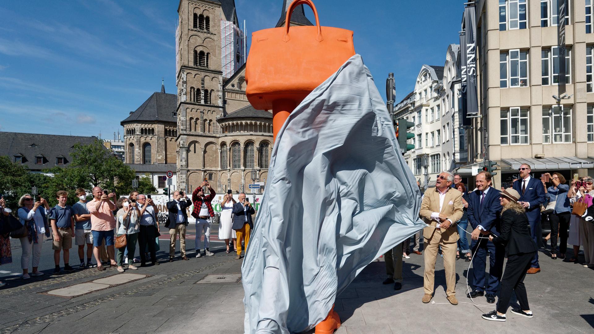 Das Kunstwerk "Walking Bag" von Erwin Wurm wird von Walter Smerling (l-r), Vorsitzender der Stiftung für Kunst und Kultur e.V. Bonn, Alexander Graf Lambsdorff, stellvertretender Vorsitzender der FDP-Bundestagsfraktion, und Birgit Schneider-Bönninger, Dezernentin für Sport und Kultur der Stadt Bonn, enthüllt. Bei dem Kunstwerk handelt es sich um eine riesige Tasche auf zwei Beinen.