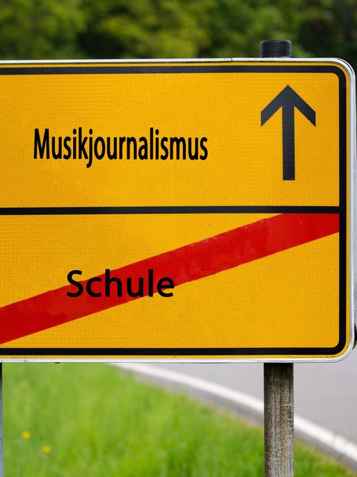 Wir sehen ein gelbes Straßenschild, auf dem in schwarzer Schrift "Musikjournalismus" steht. 