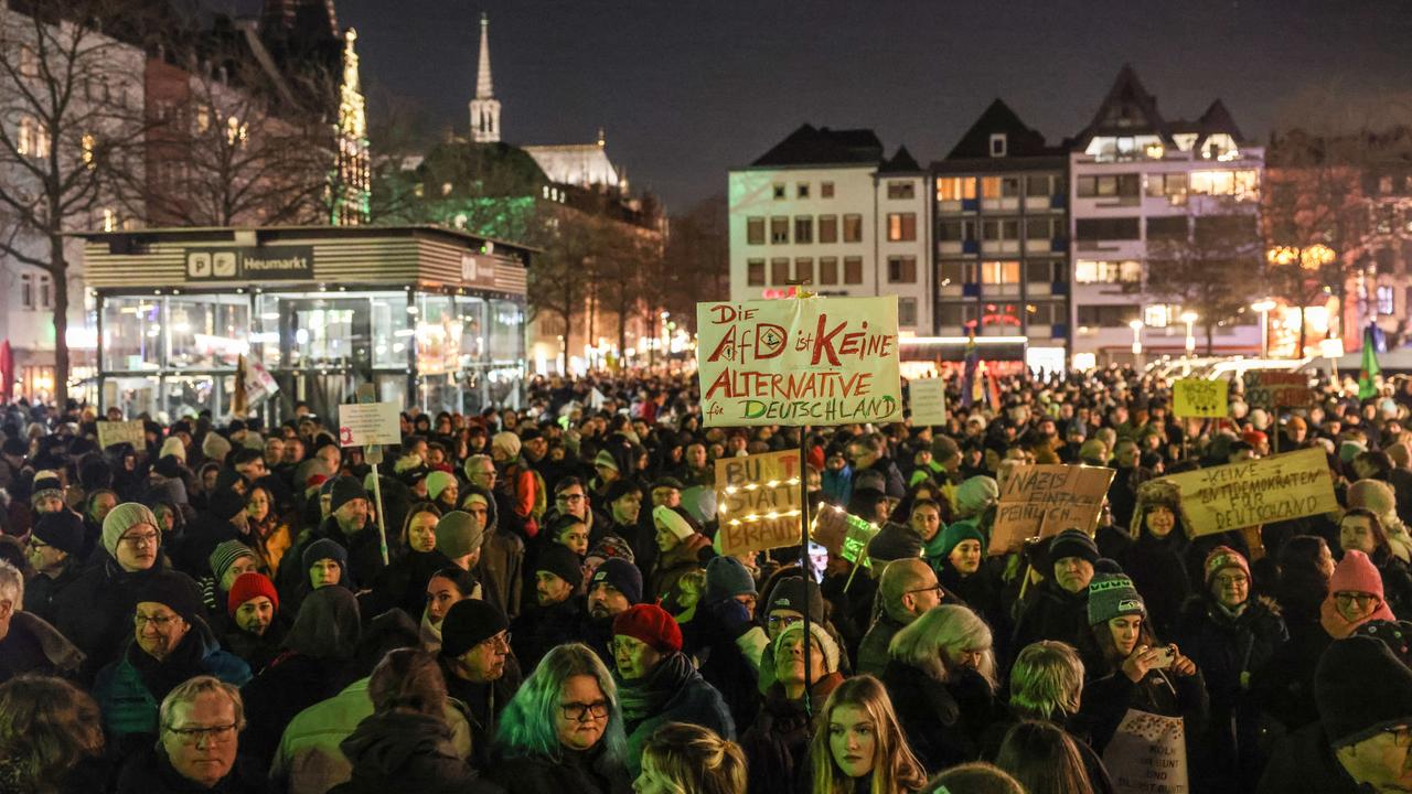 Eine große Menge an Demonstranten steht auf einem großen Platz. Dahinter eine beleuchtete Häuserzeile.