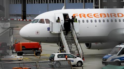 Blick aus der Ferne auf den vorderen Teil einer weißen Passagiermaschine mit der Aufschrift "Freebird" mit einer Gangway und einer offenen Tür. 