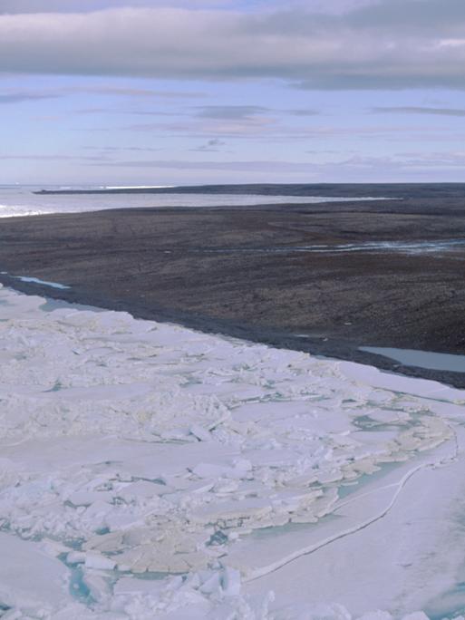 Blick über eine durch Dauerfrost (Permafrost) gezeichnete Landschaft auf der zur Russland gehörenden Bolschewik Insel. Während im Vordergrund noch Packeis herrscht, ist die Landschaft im Hintergrund schon aufgetaut und schlammig. Aufnahme: 24.08.1999