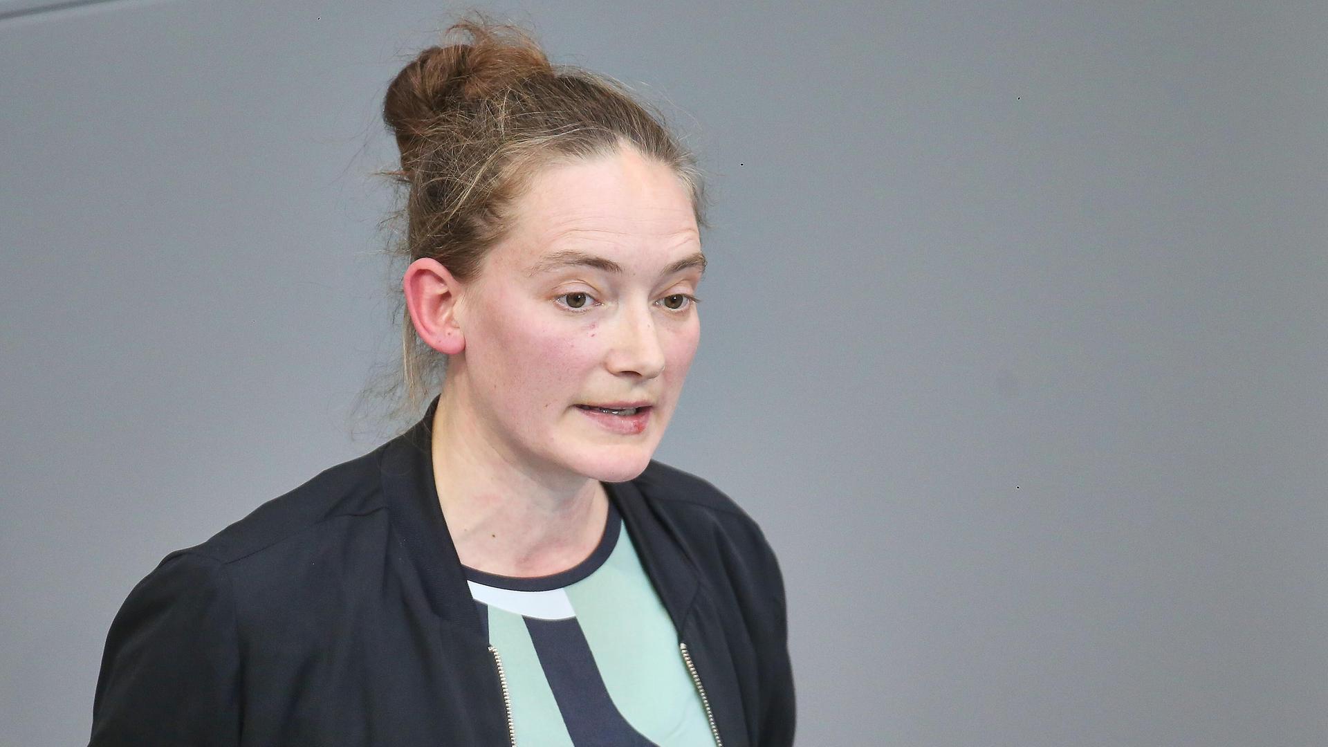 Die Linken-Politikern Violetta Bock steht am Rednerpult im Bundestag. Sie trägt einen schwarzen Blazer.