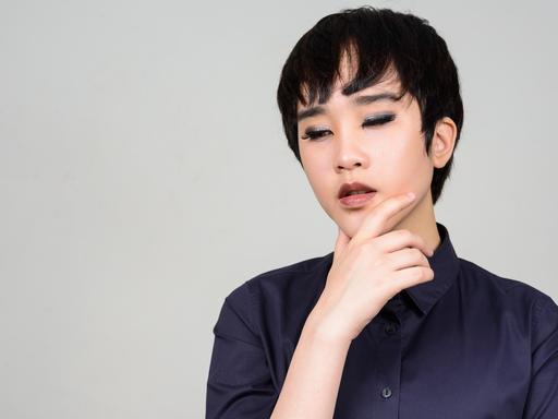 Eine junge, asiatische Transgenderfrau vor weißem Hintergrund