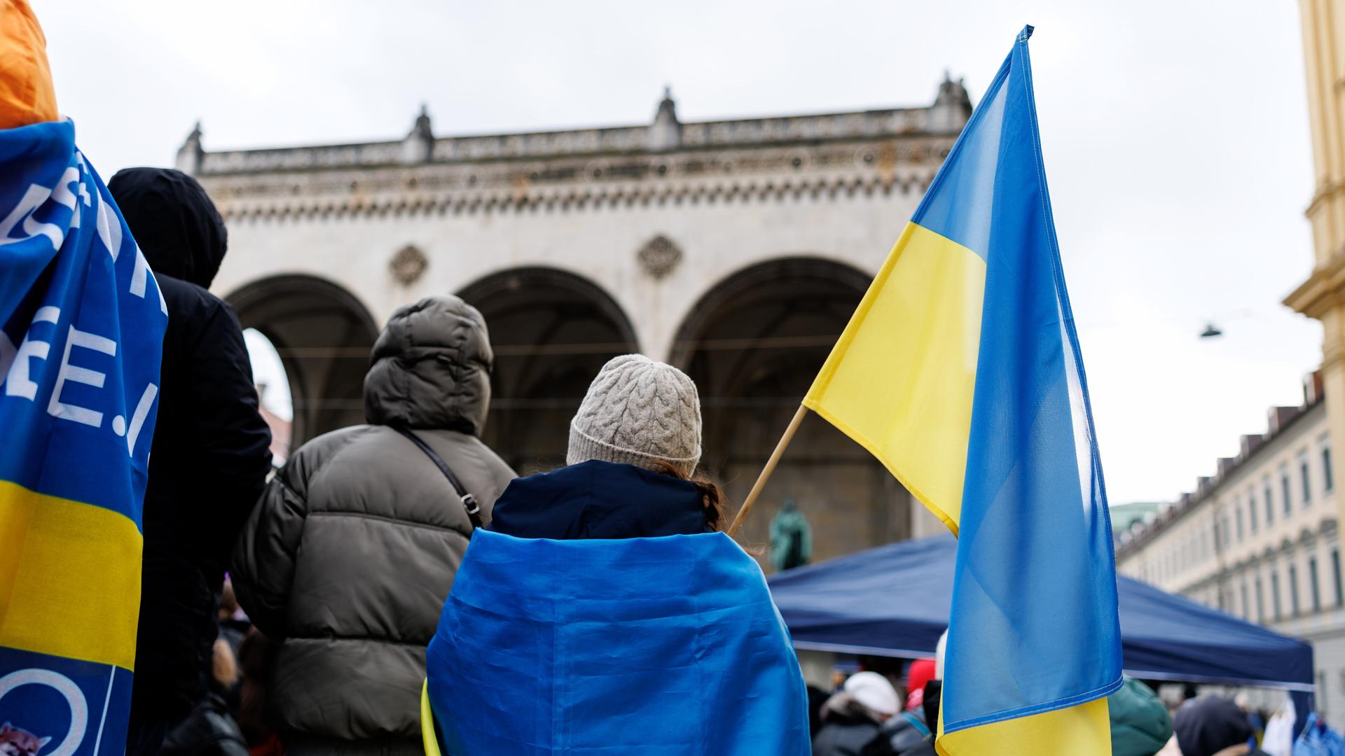 Teilnehmende einer Solidaritätsdemo mit der Ukraine demonstrieren mit ukrainischen Flaggenauf dem Odeonsplatz in München.