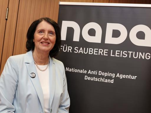 Andrea Gotzmann steht vor einem Plakat der Nationalen Anti Doping Agentur. Unter dem Schriftzug NADA steht "Für saubere Leistung".